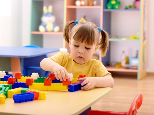 Little girl play with building bricks in preschool