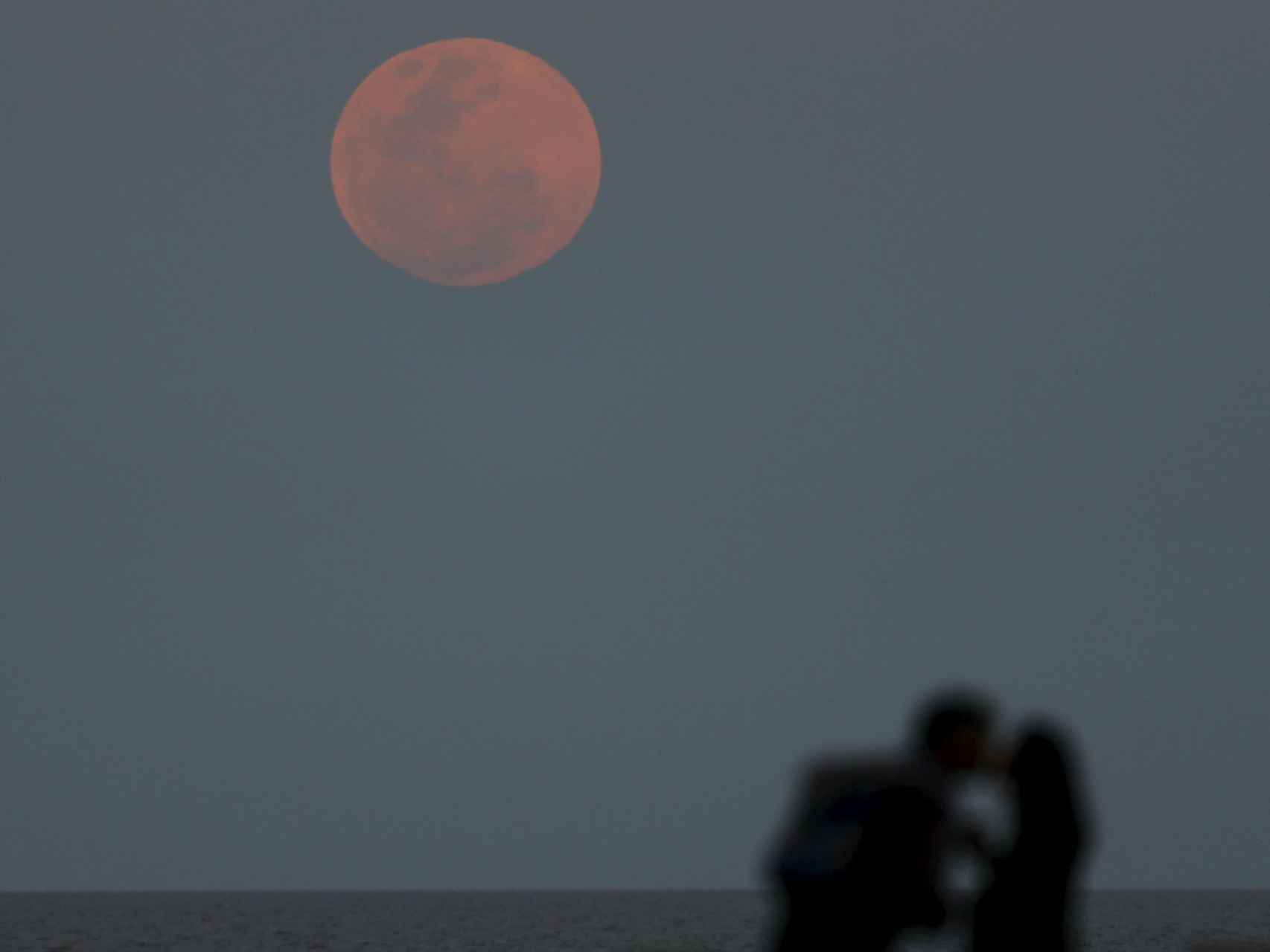 Una pareja se besa ante la luna roja sobre el Río de La Plata en Buenos Aires.