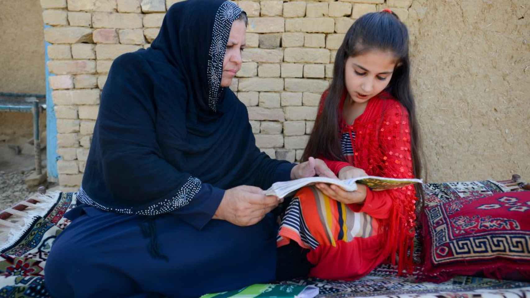 La profesora afgana Aqeela Asifi ayuda con los deberes a su hija pequeña Sawera.