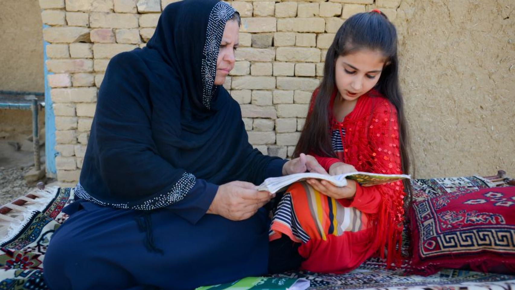 La profesora afgana Aqeela Asifi ayuda con los deberes a su hija pequeña Sawera.