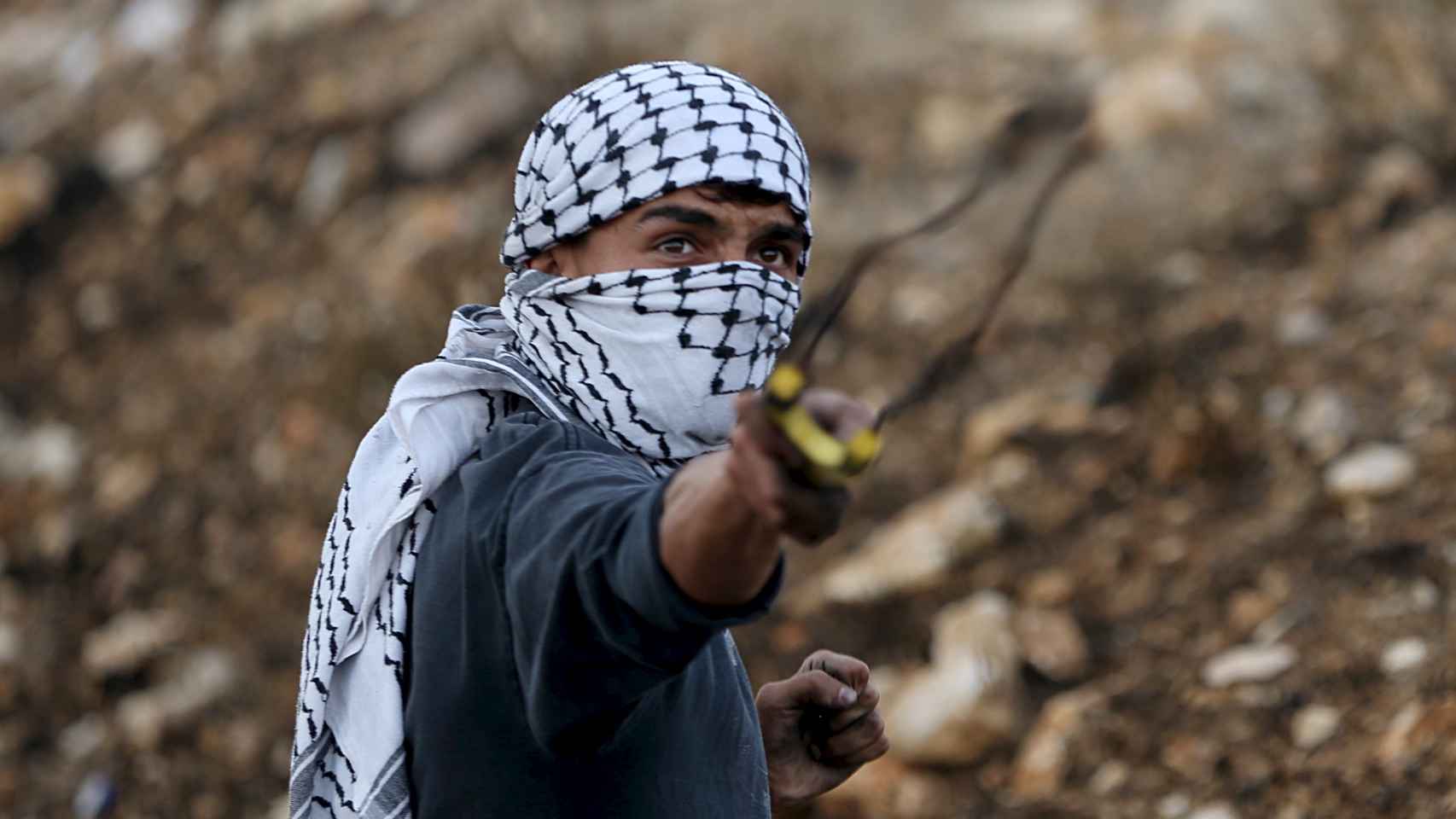 Un palestino lanza piedras con un tirachinas contra el Ejército israelí.