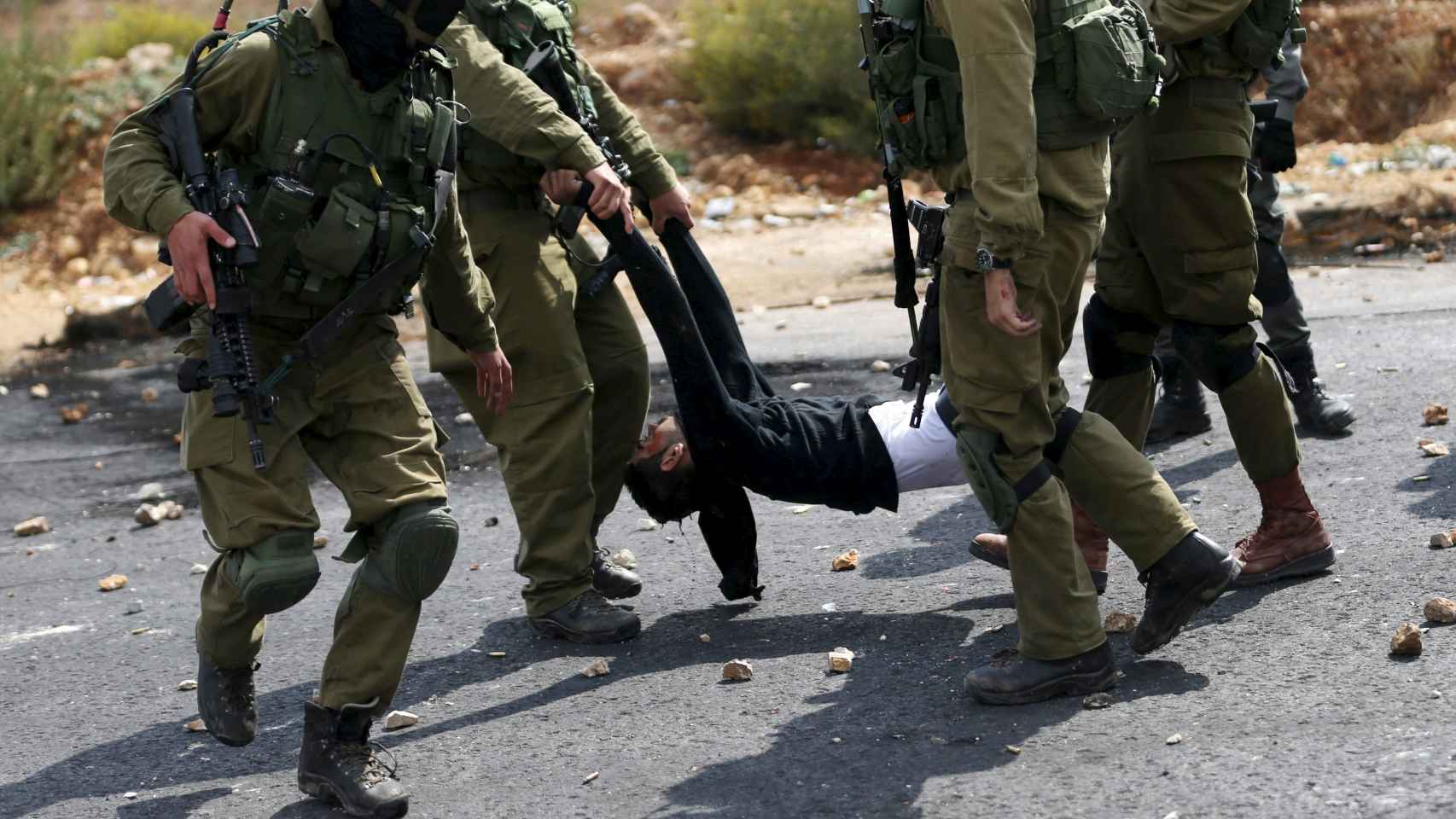 Soldados israelíes detienen a un palestino herido cerca de Ramala