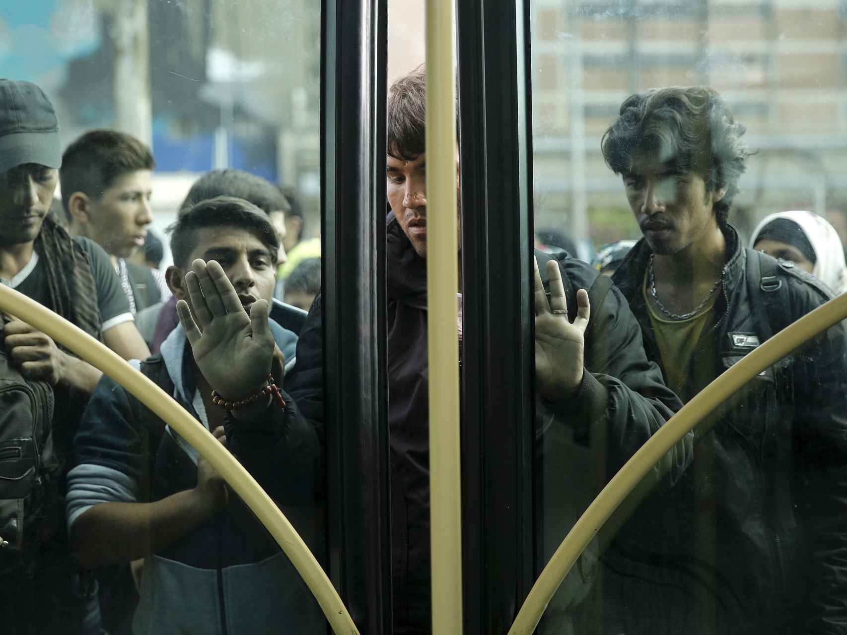 Un grupo de inmigrantes intenta entrar en un autobús tras desembarcar en el puerto del Pireo, en Atenas