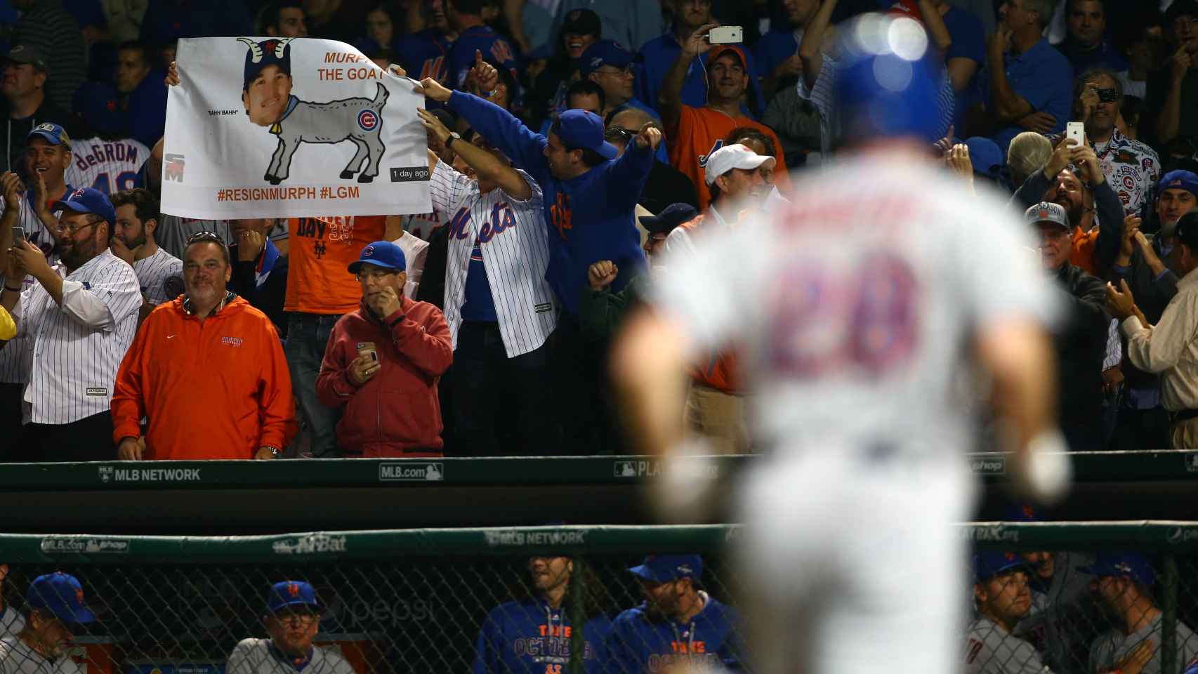 Unos aficionados recuerdan la maldición en formato póster, mientras los Mets anotan.