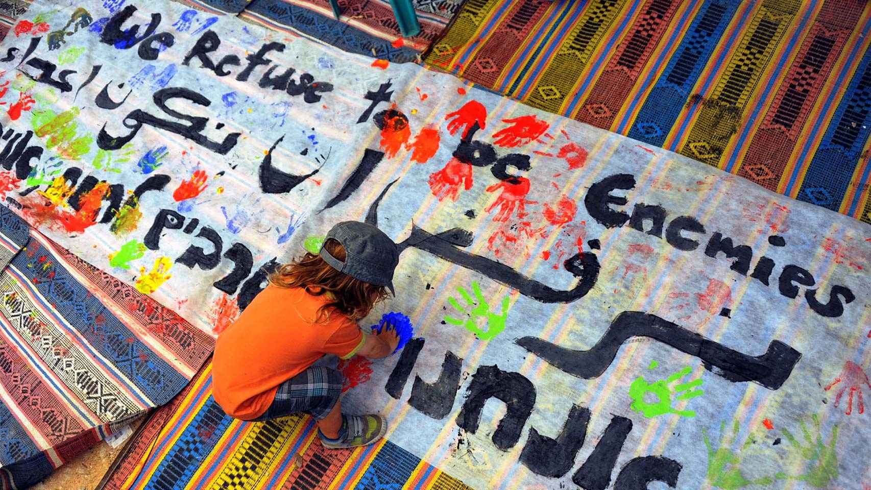 Un niño pinta un mural con mensajes pacifistas.