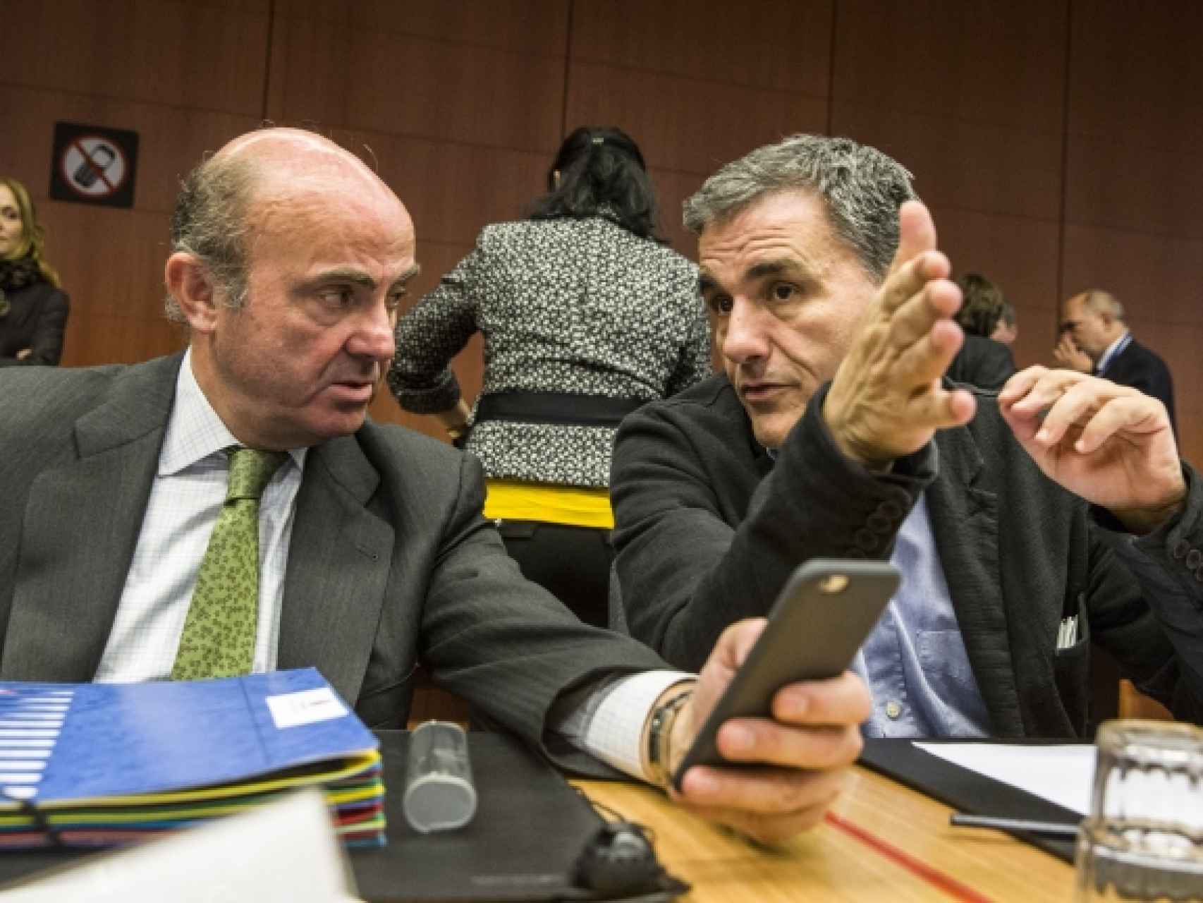 El ministro de Economía, Luis de Guindos, conversa durante el Eurogrupo con su colega griego, Euclides Tsakalotos
