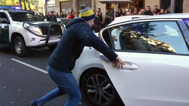 El familiar de uno de los detenidos se abalanza sobre el coche de las fuerzas del orden.