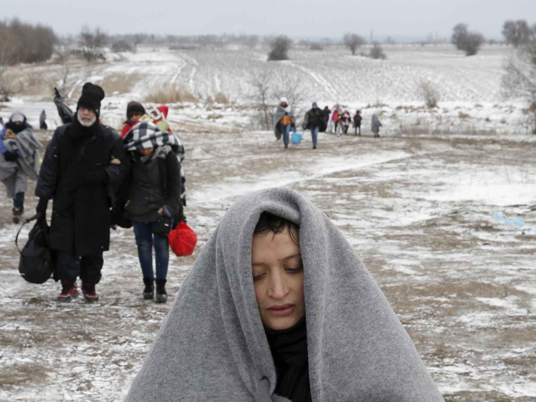 Un grupo de refugiados camina por el campo tras cruzar la frontera entre Macedonia y Serbia