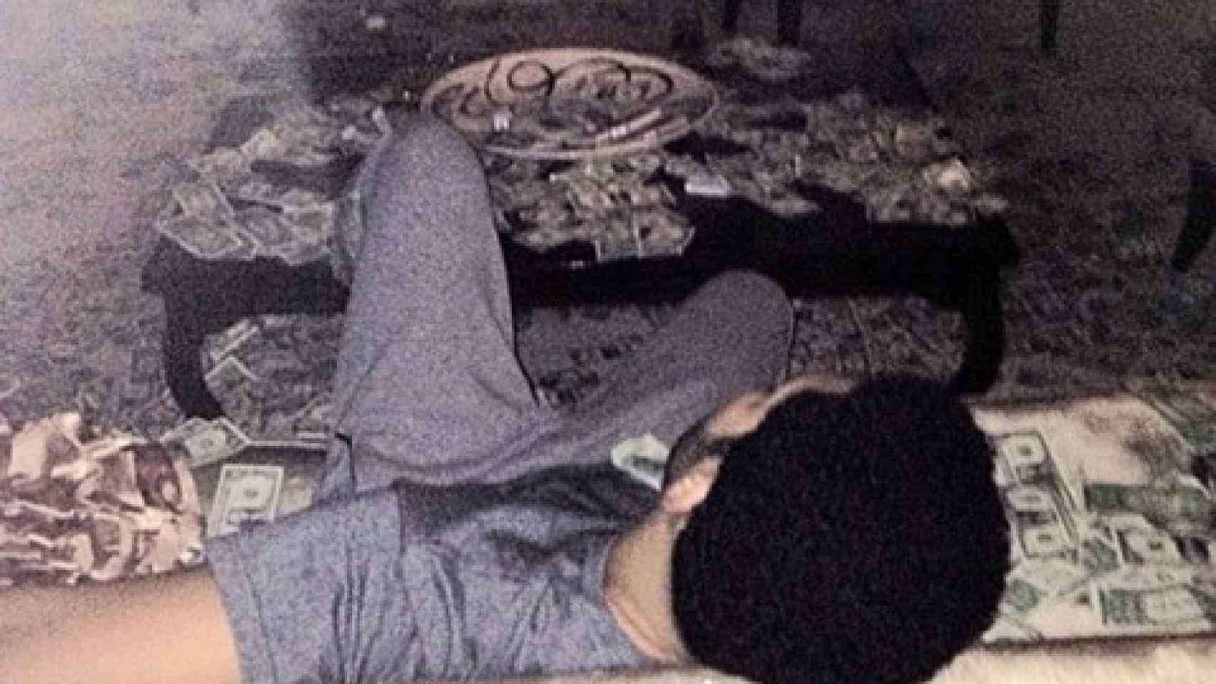 Drake tumbado en el sofá de su casa rodeado de billetes
