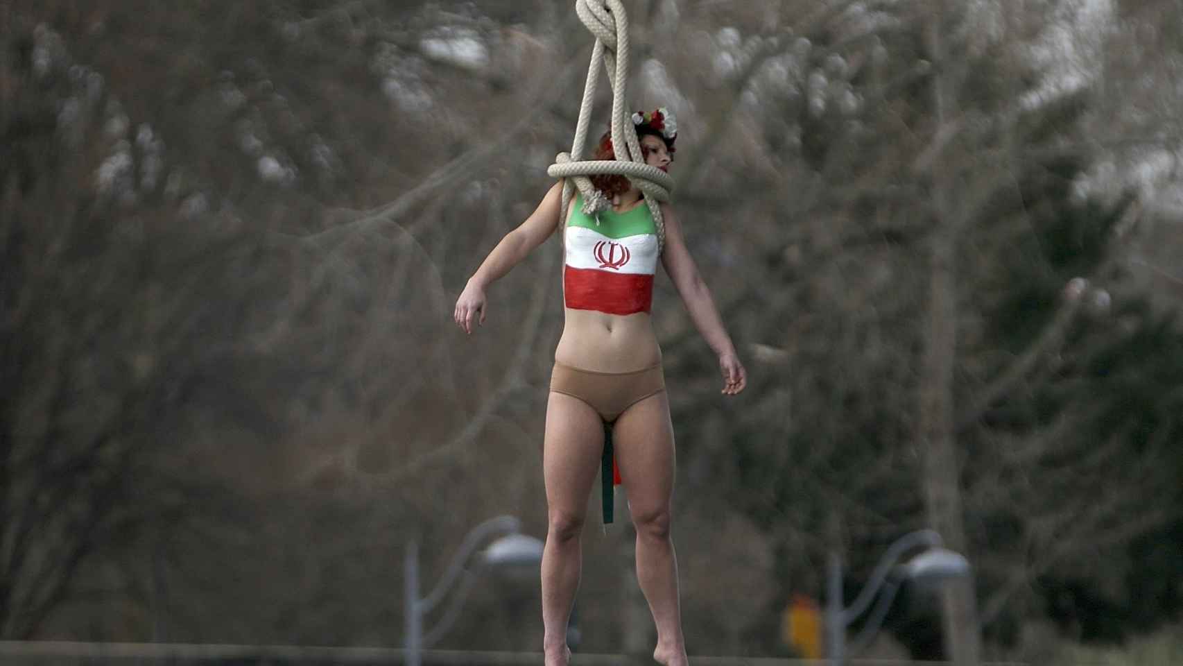 Una activista de Femen con una bandera iraní pintada en el pecho cuelga de un puente