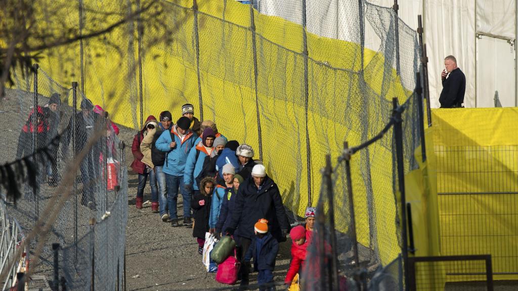 Refugiados caminan junto a una valla en la frontera de Austria con Eslovenia.