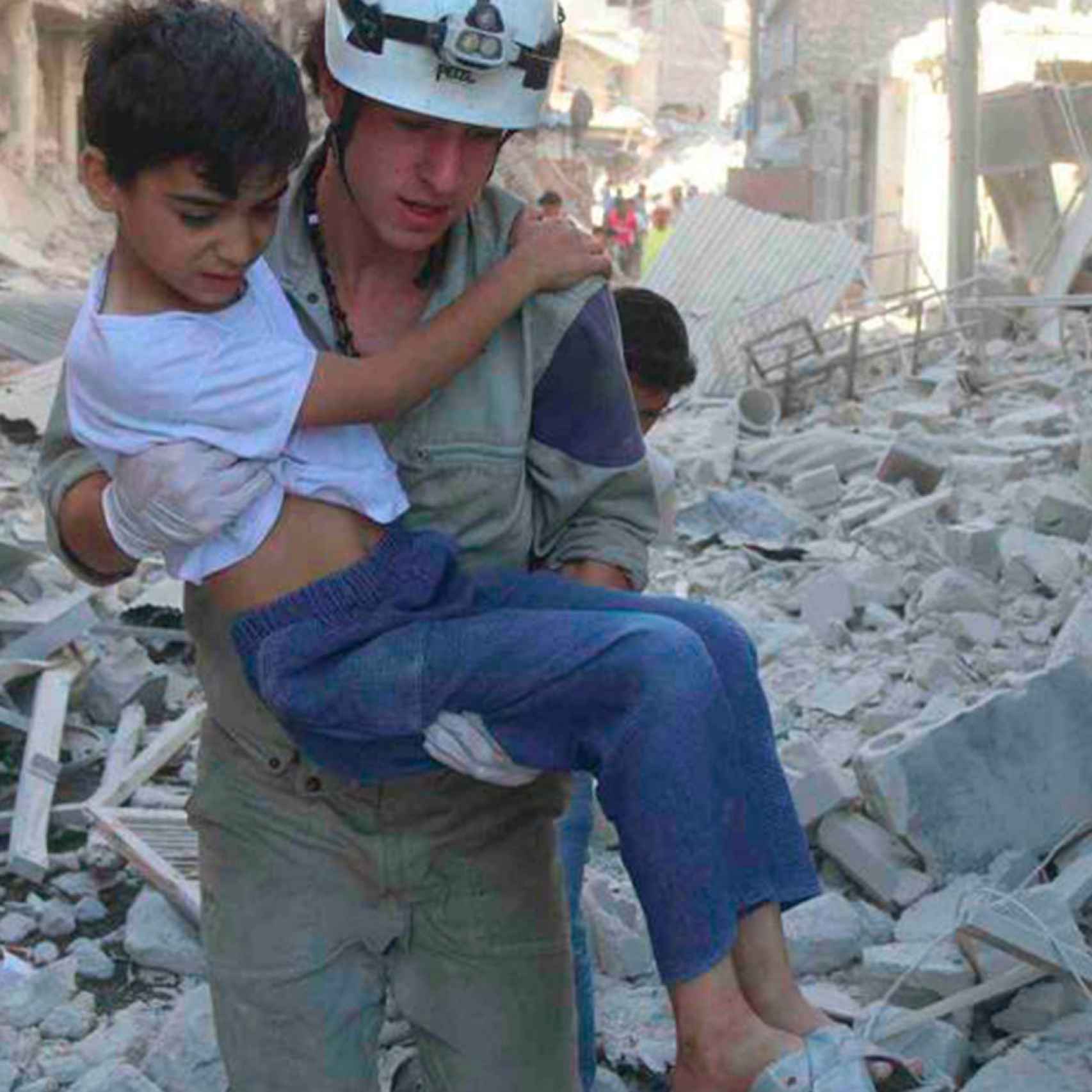 Un voluntario ayuda a un niño víctima de los bombardeos.
