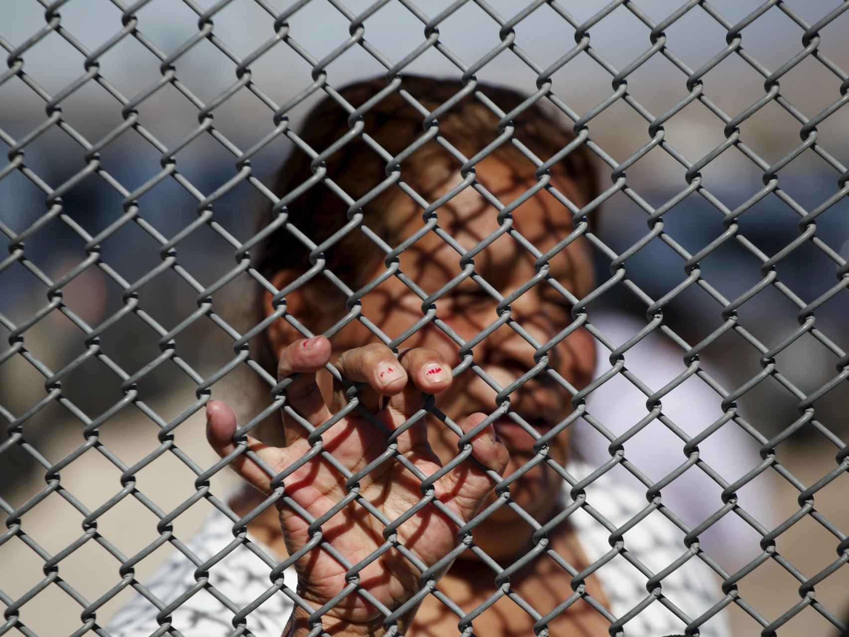 Una migrante  habla con su familia a través de la valla entre Juárez y El Paso.