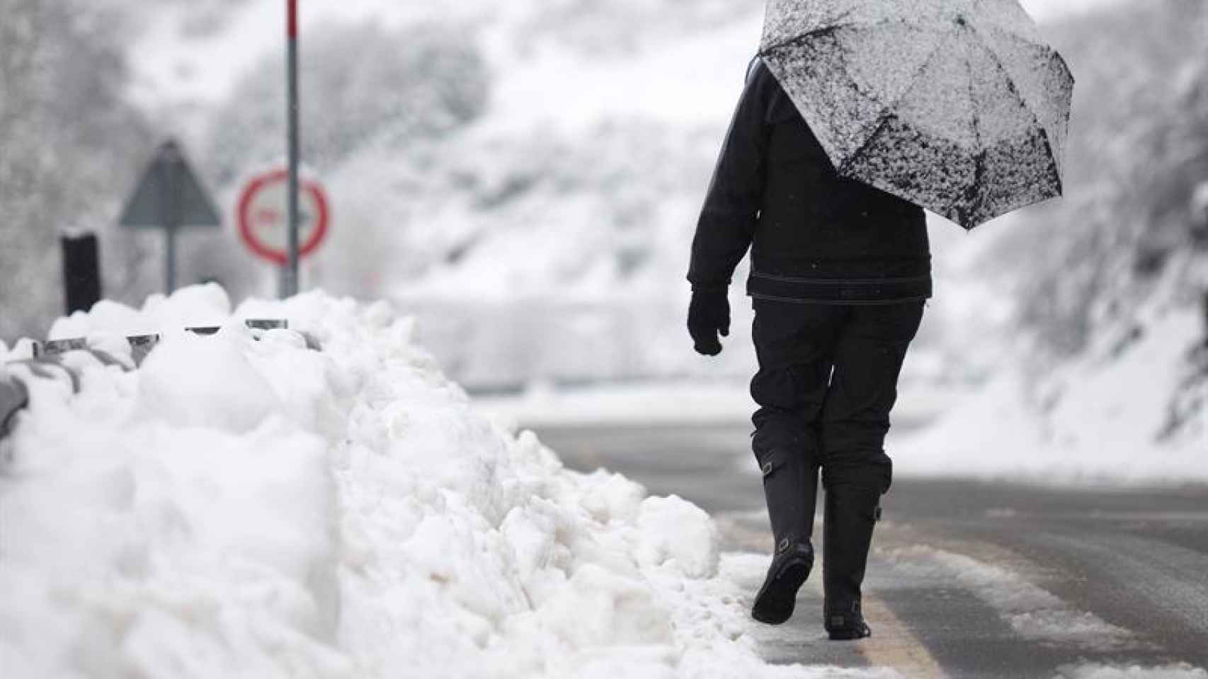 Una mujer camina entre la nieve por una carretera de Lugo
