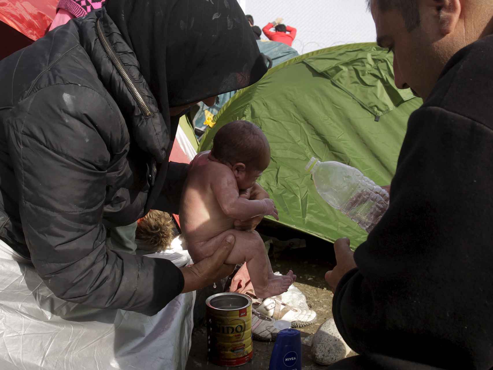 Dos refugiados y su bebé en la frontera entre Grecia y Macedonia