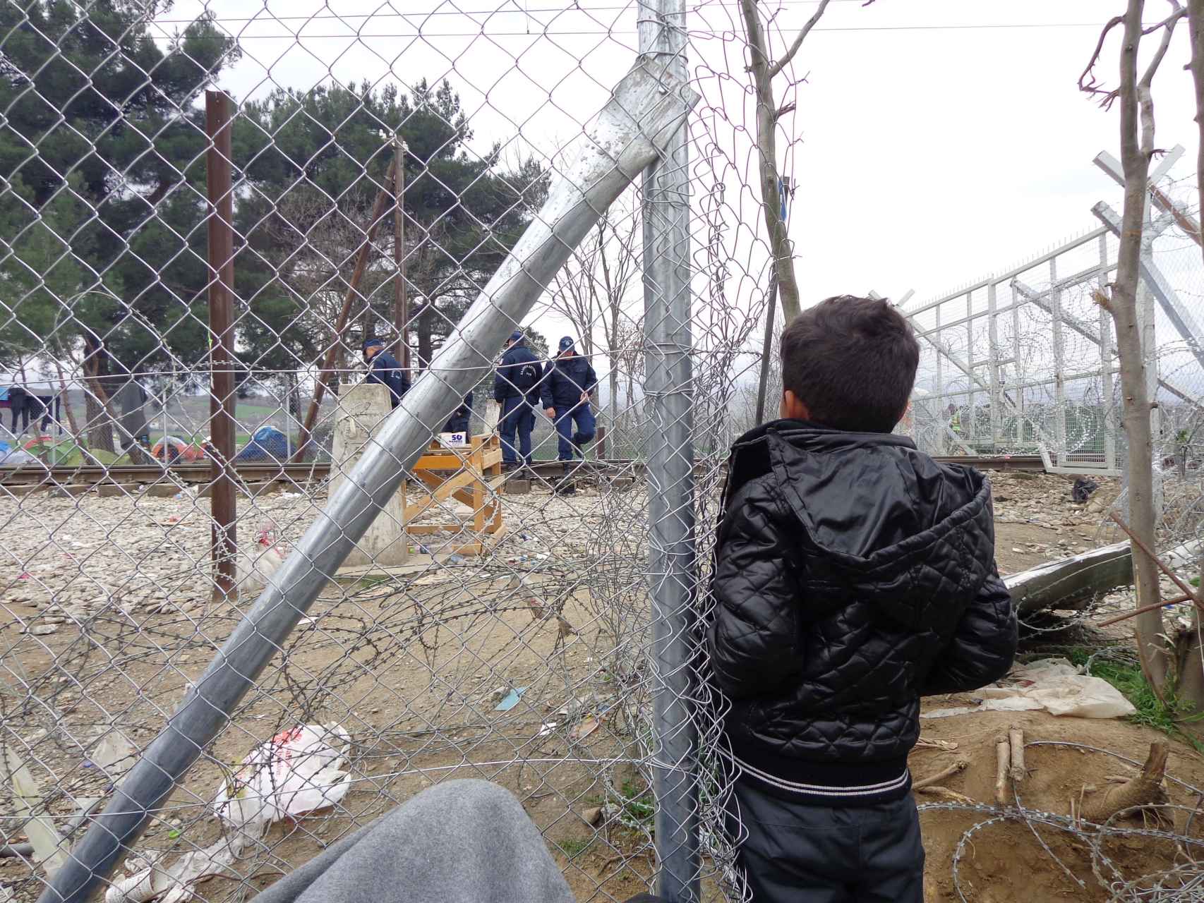 Un niño observa a la Policía junto a la valla que separa Grecia de Macedonia.