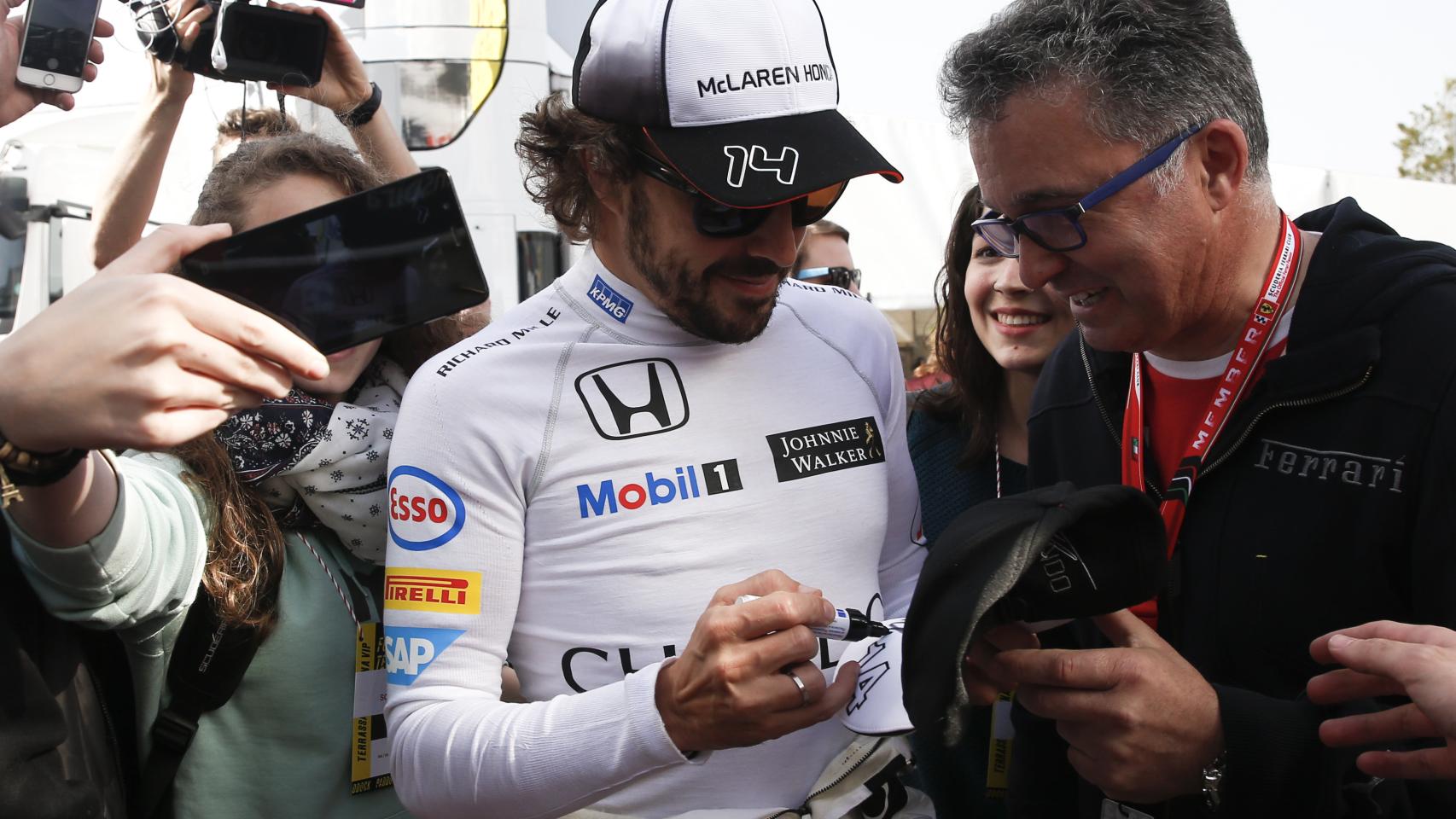 Fernando Alonso firma un autógrafo a un aficionado.