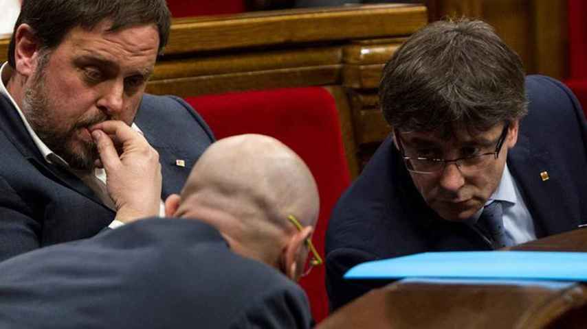 Raül Romeva y Puigdemont conversan en el Parlament bajo la mirada de Oriol Junqueras.