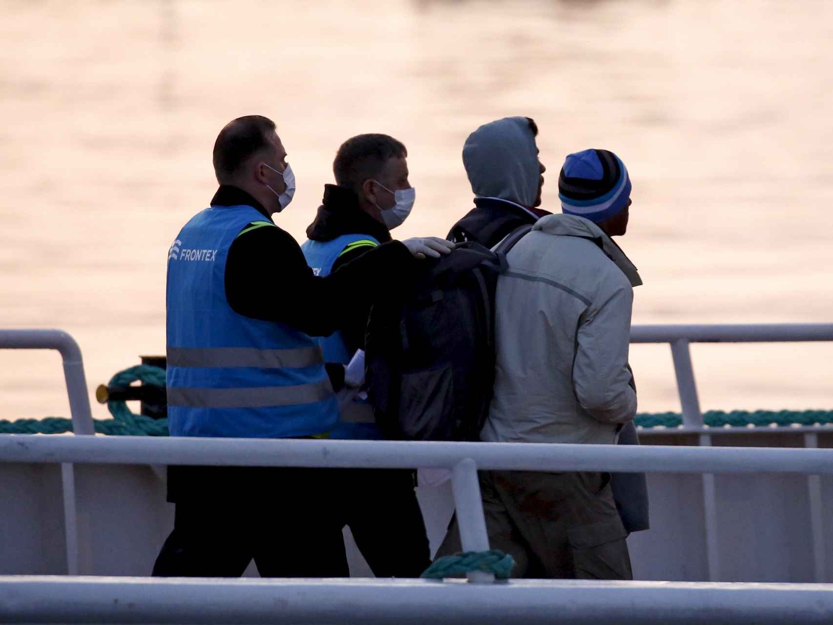 Agentes turcos escoltan a los primeros migrantes deportados bajo una señal de la seguridad, primero.
