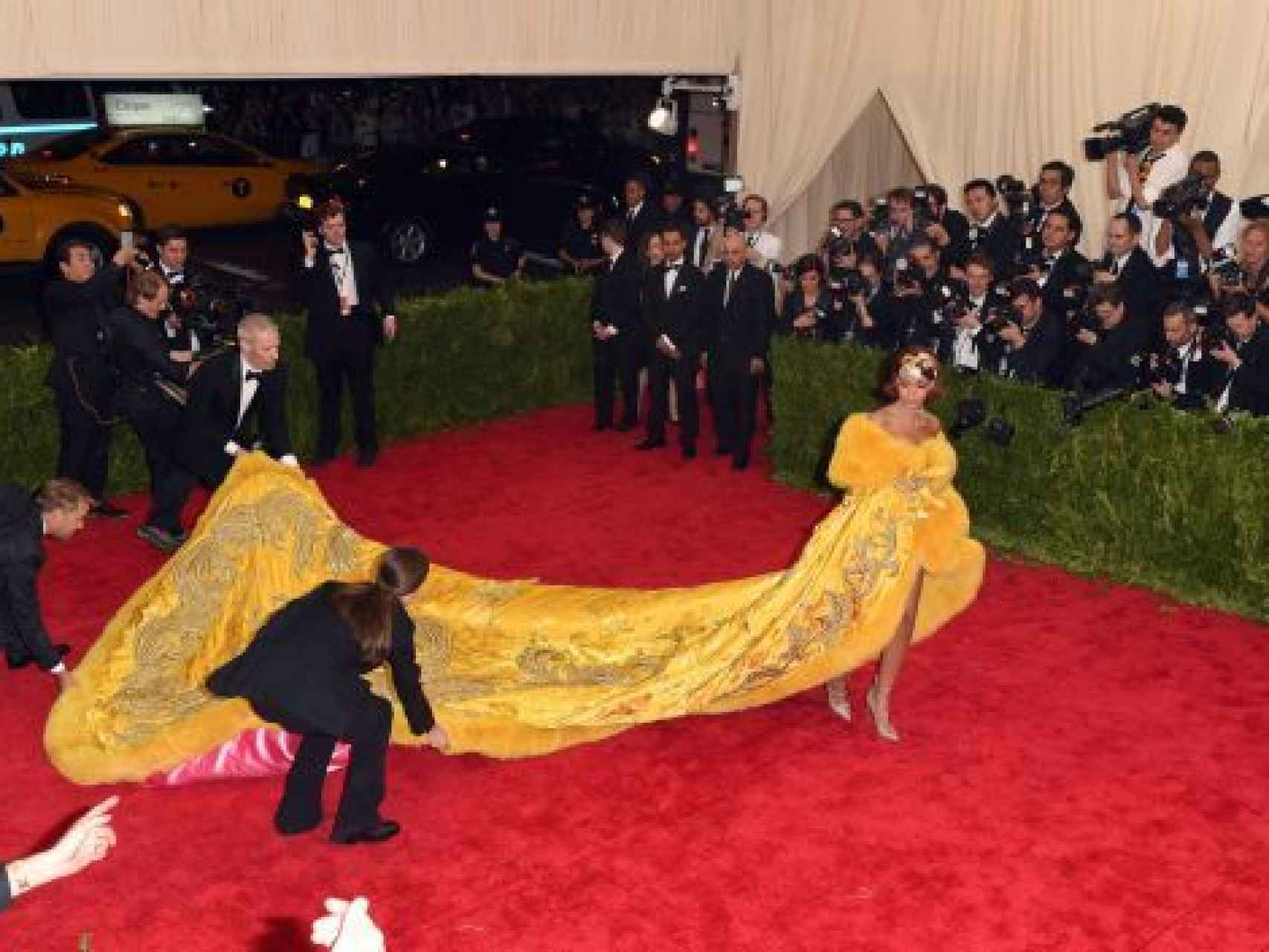 Rihanna es ayudada para colocarse en el photocall de la Gala del Met en 2015