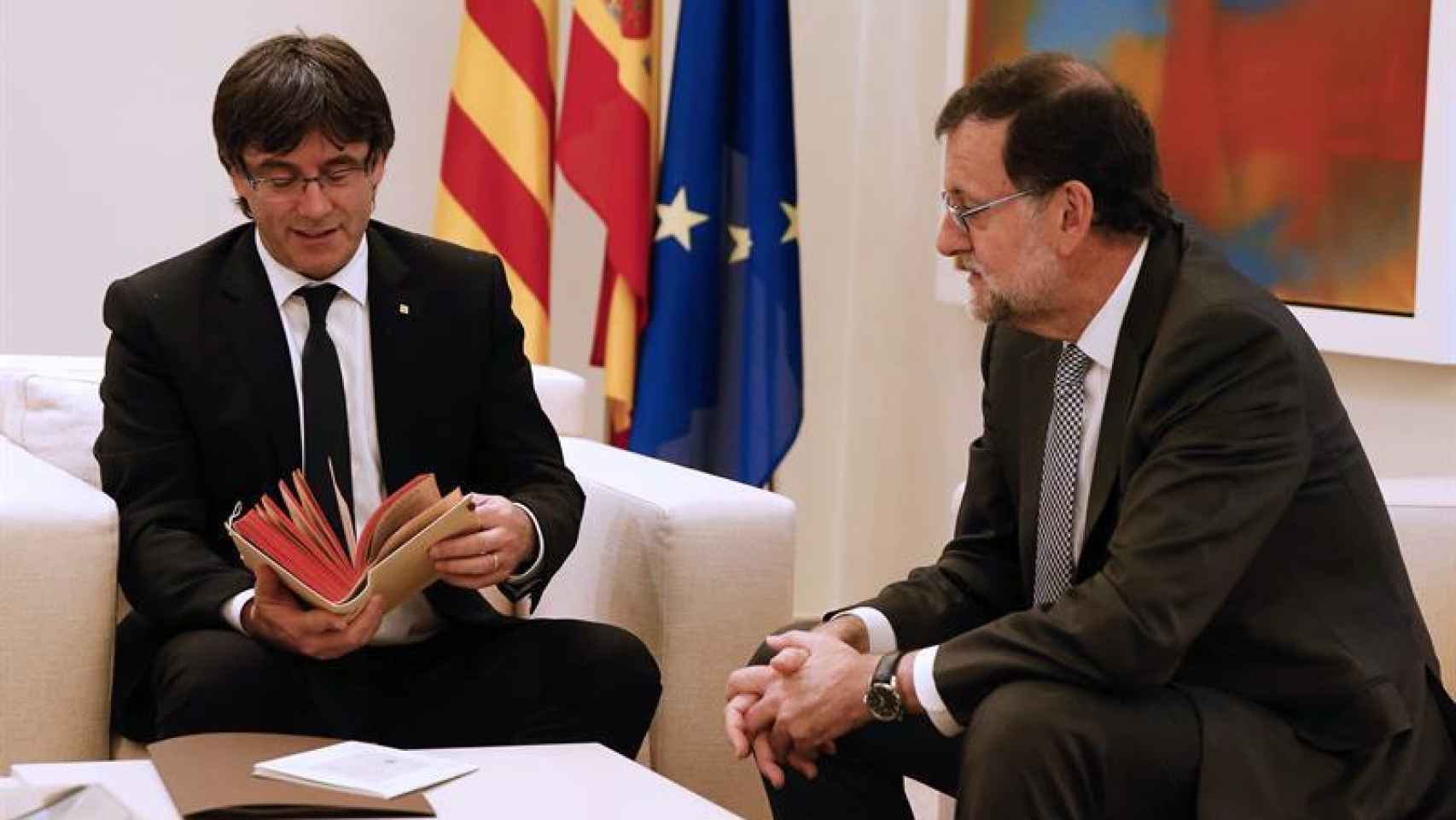 Puigdemont ojeando el regalo de Rajoy durante su reunión en Moncloa