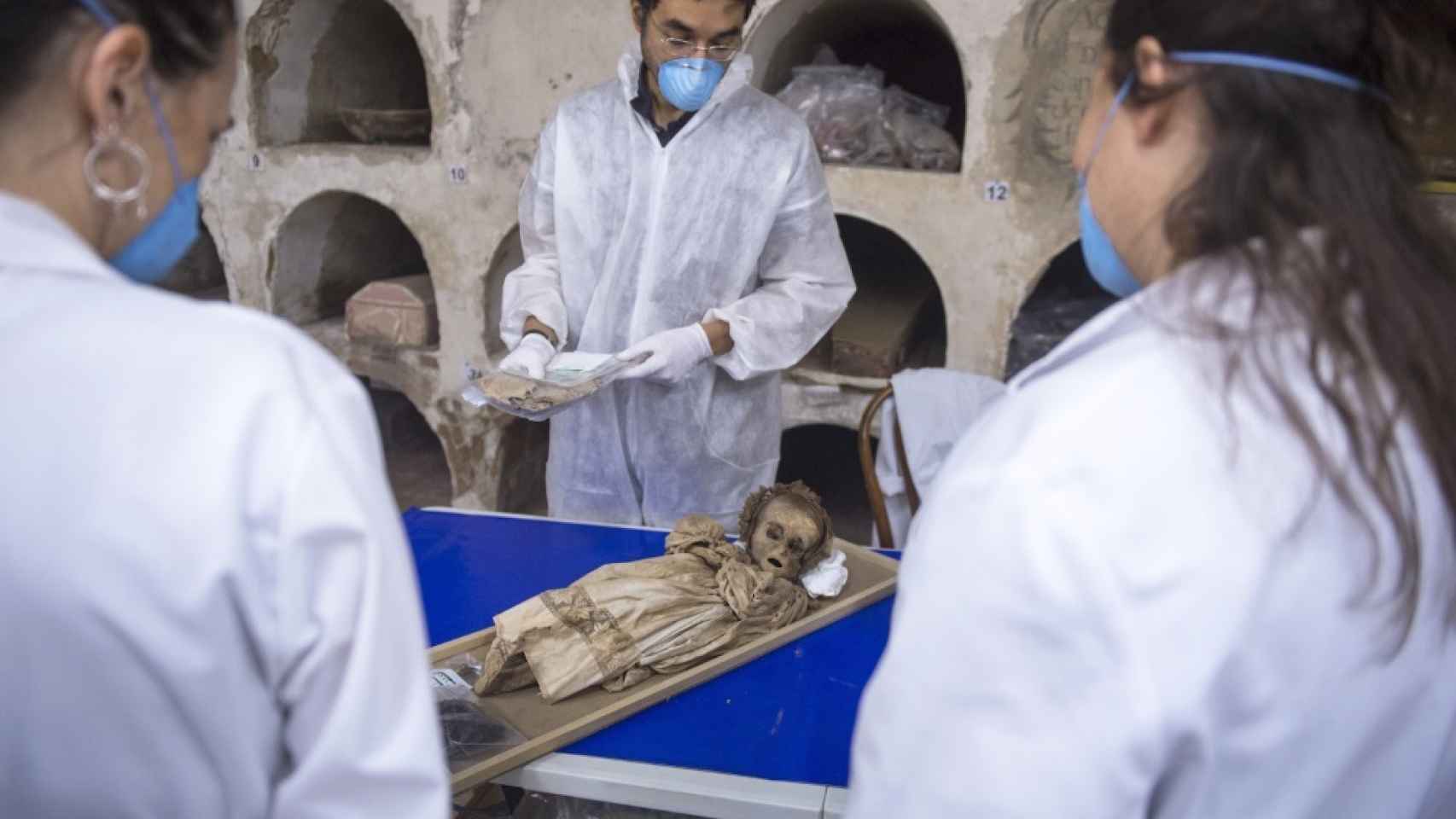García Rubio, Martínez y Ríos, observan los restos momificados de uno de los niños.