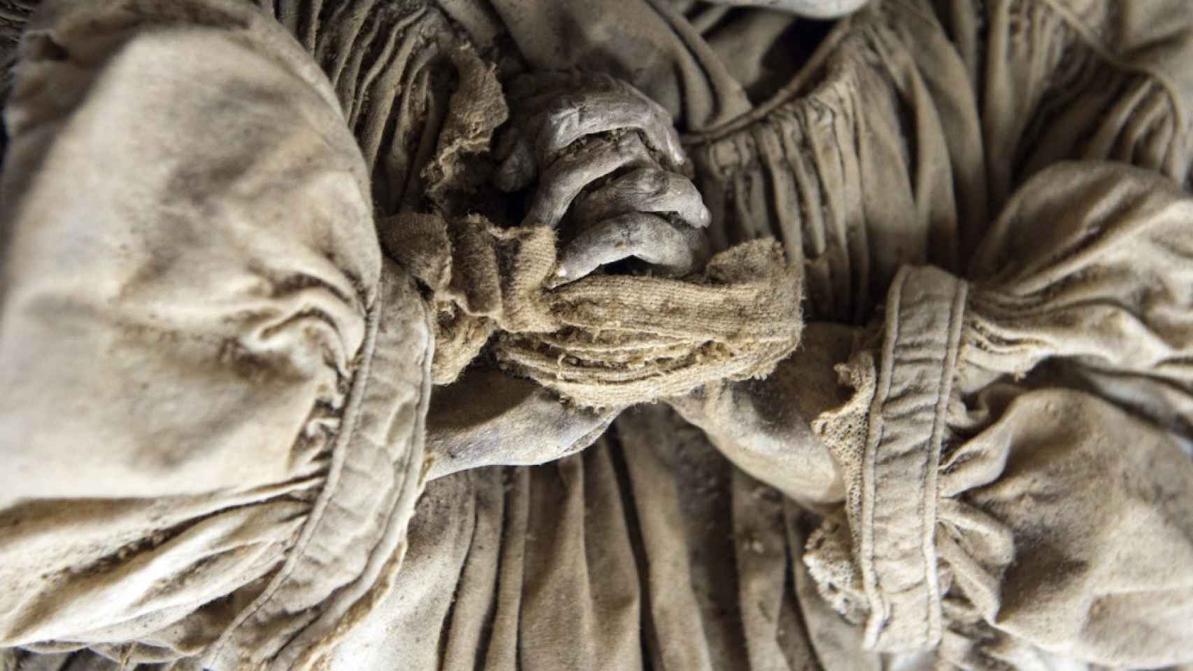 Detalle de las manos entrelazadas y sujetas con una tela de uno de los restos momificados.