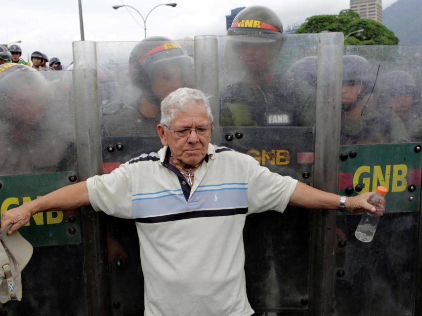 Un opositor se pone ante la Guardia Nacional durante una manifestación contra Maduro.