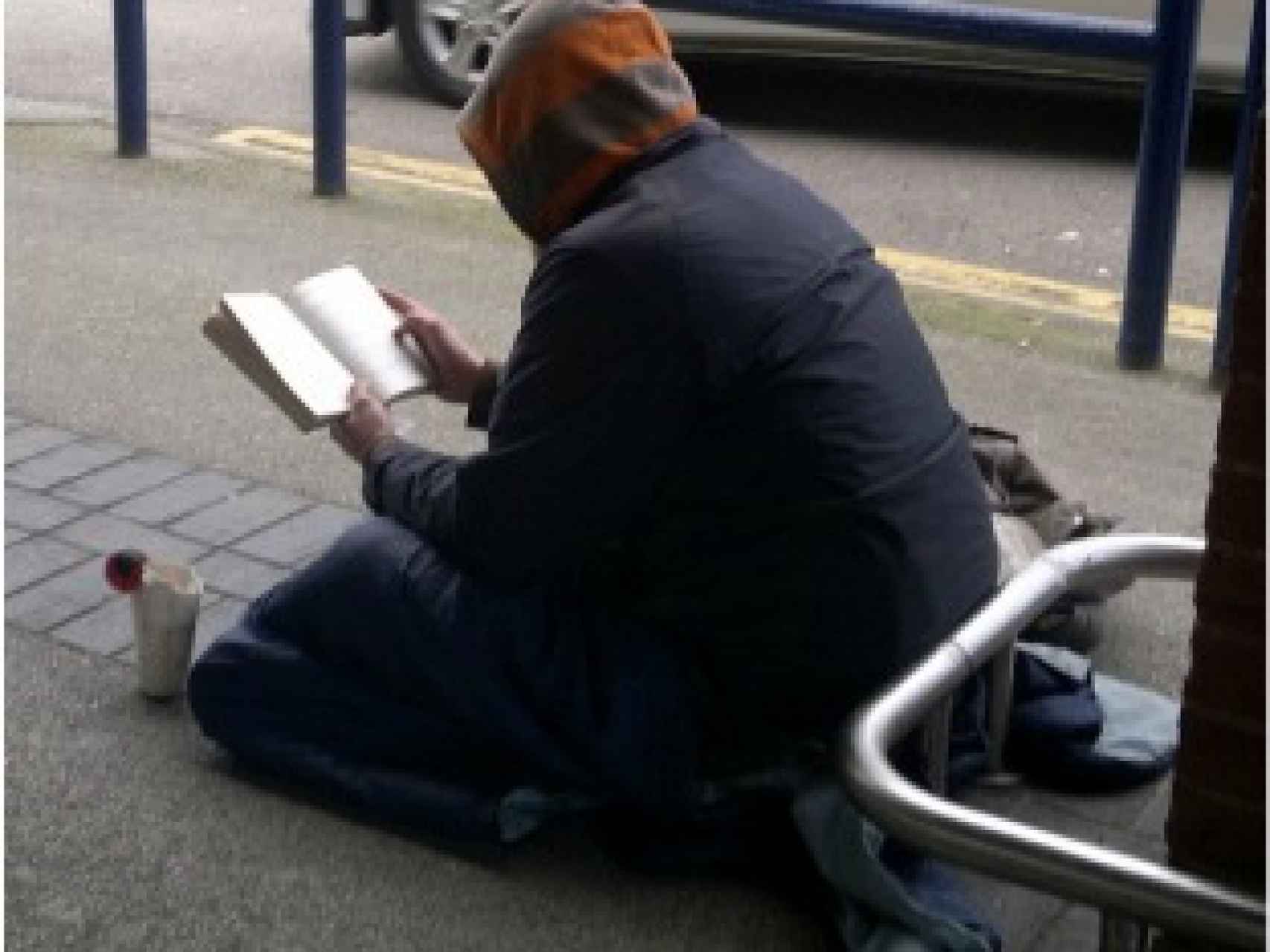 Una persona sintecho leyendo en la calle.