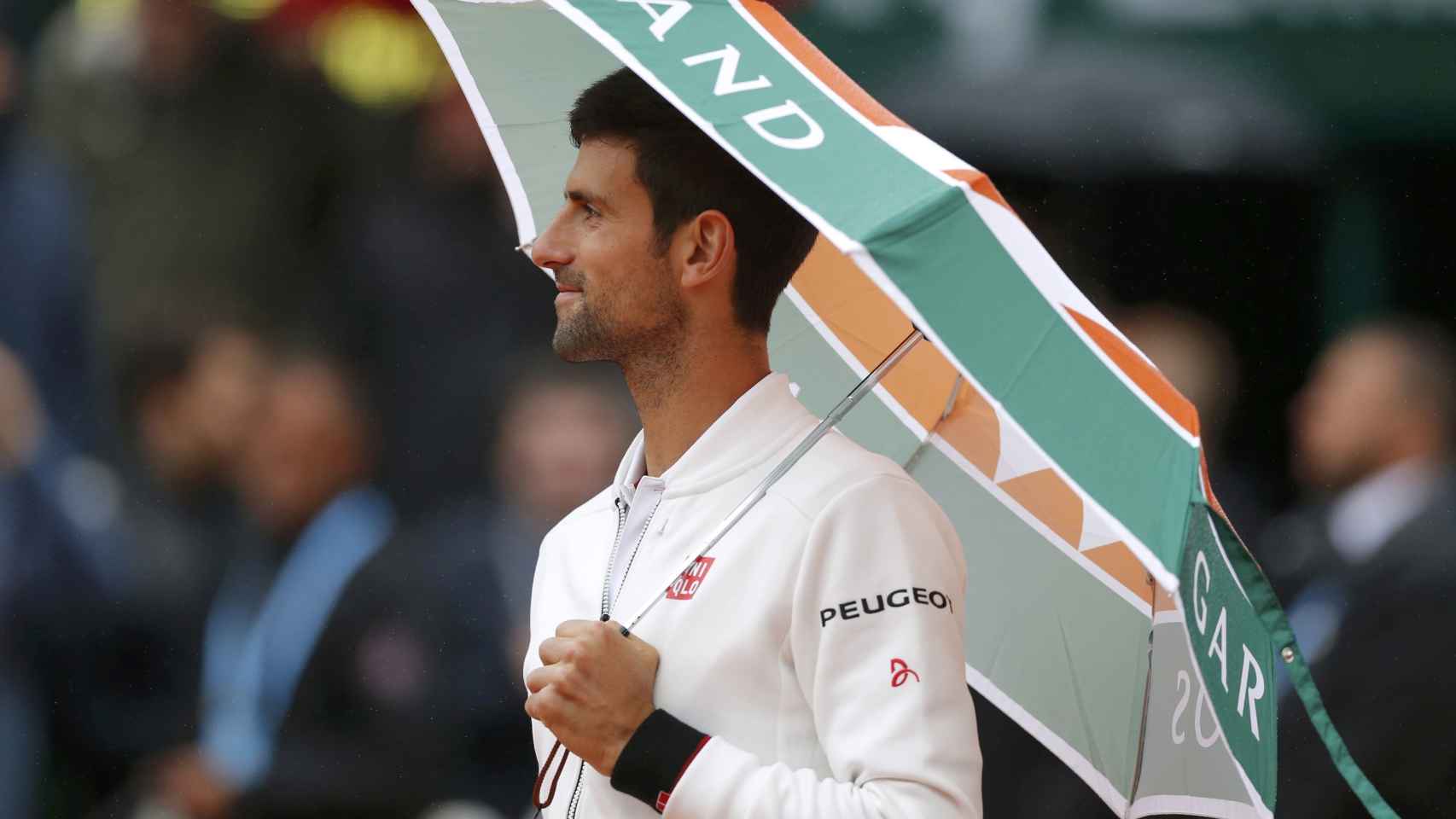 Djokovic, paragüa en mano refugiándose de la lluvia.