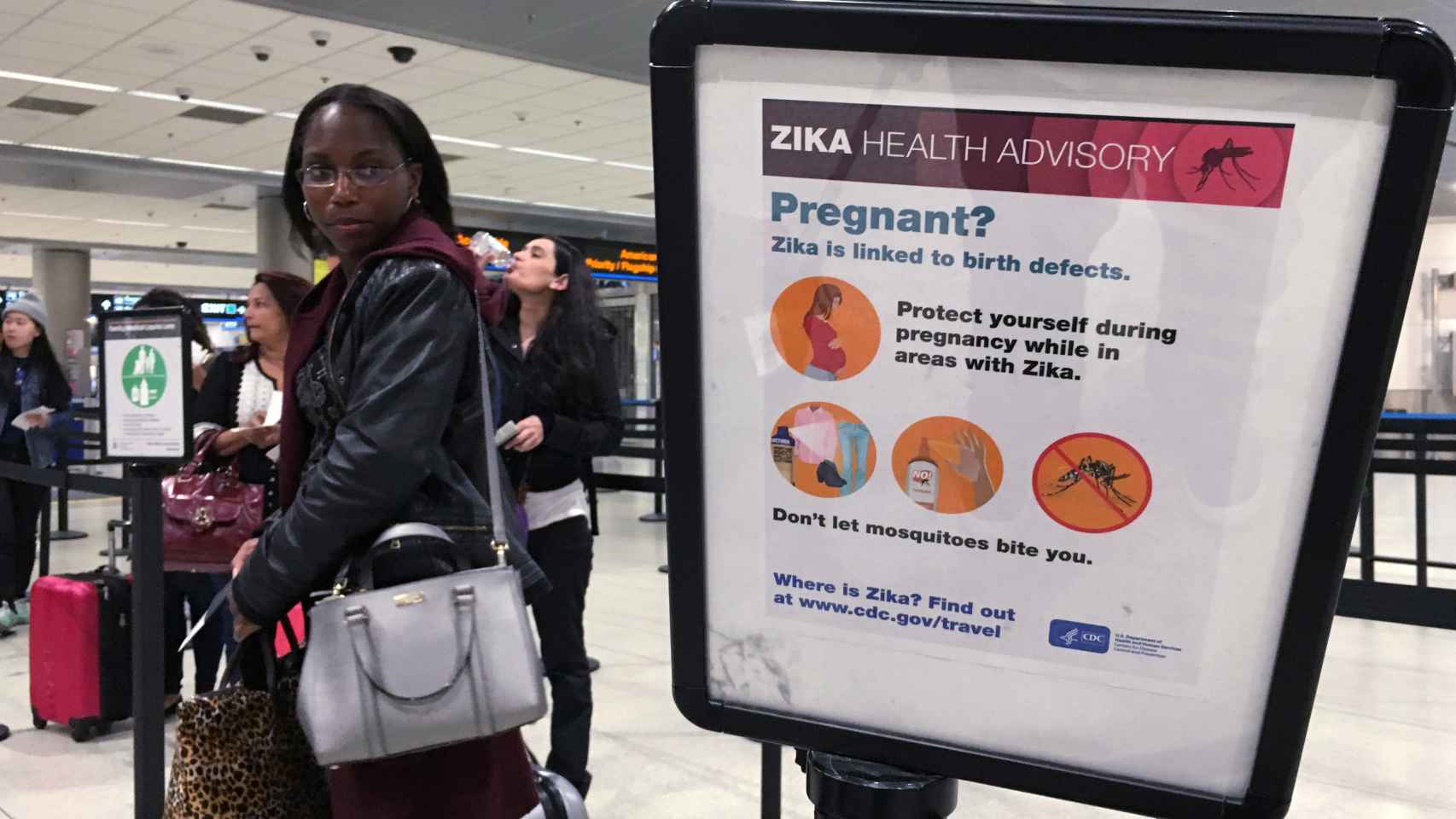 Una mujer observa un cartel que advierte del riesgo de Zika en Miami.