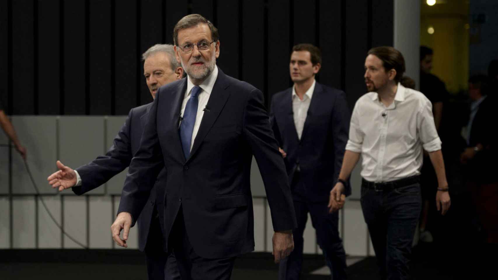 Mariano Rajoy en primer plano, con Iglesias y Rivera al fondo.
