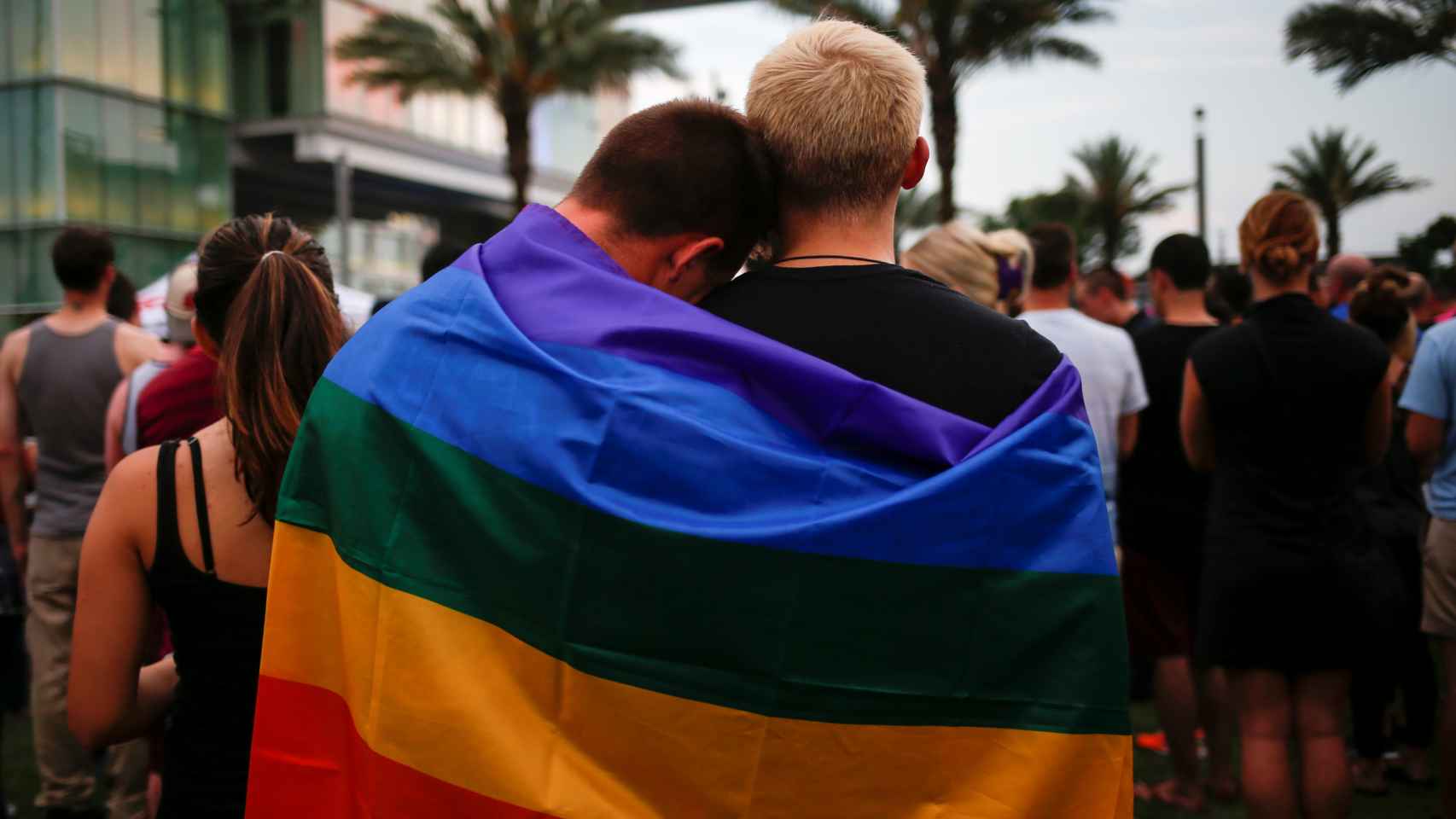 Dos hombres se cubren con la bandera multicolor durante un homenaje a las víctimas de Orlando