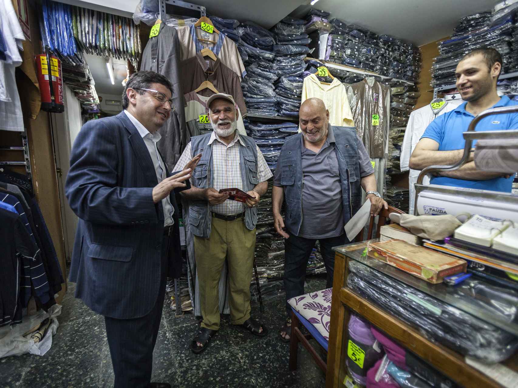El número seis del PSC al Congreso conversando con otros musulmanes en una tienda de ropa.