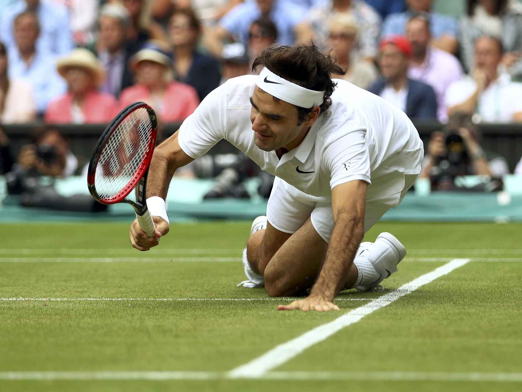Federer cae tras pelear un punto en su partido ante Raonic.
