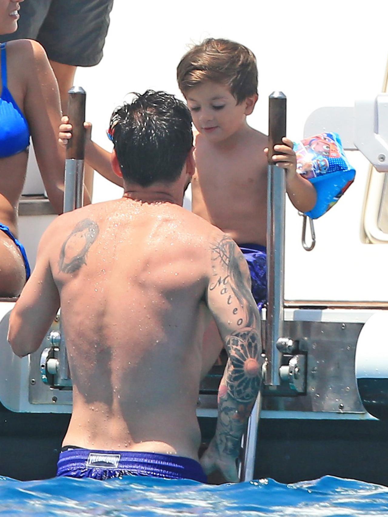 Thiago Messi se lanza al agua con ayuda de su padre.