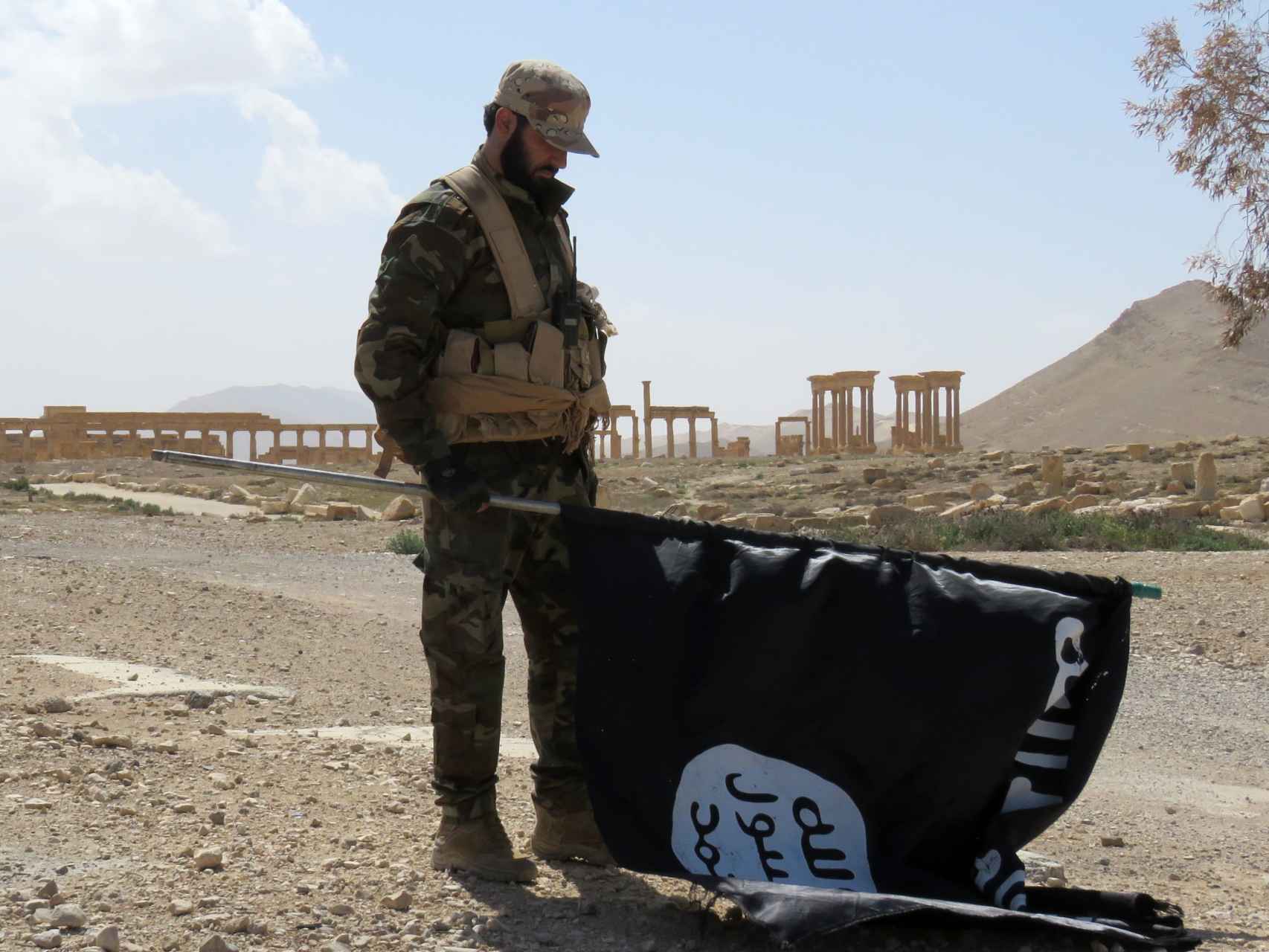 Un soldado sirio retira una bandera del Estado Islámico en Siria.