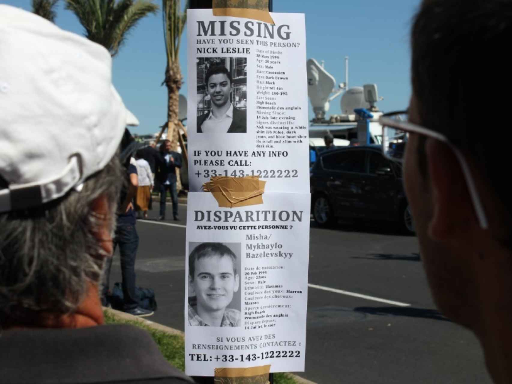 Dos hombres observan un cartel pidiendo información sobre Nick Leslie.