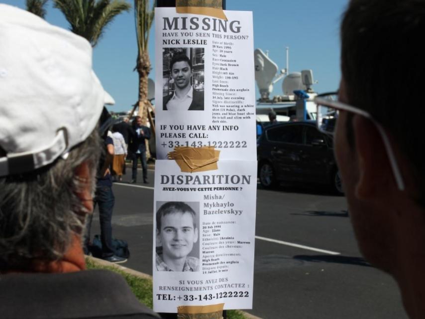 Dos hombres observan un cartel pidiendo información sobre Nick Leslie.