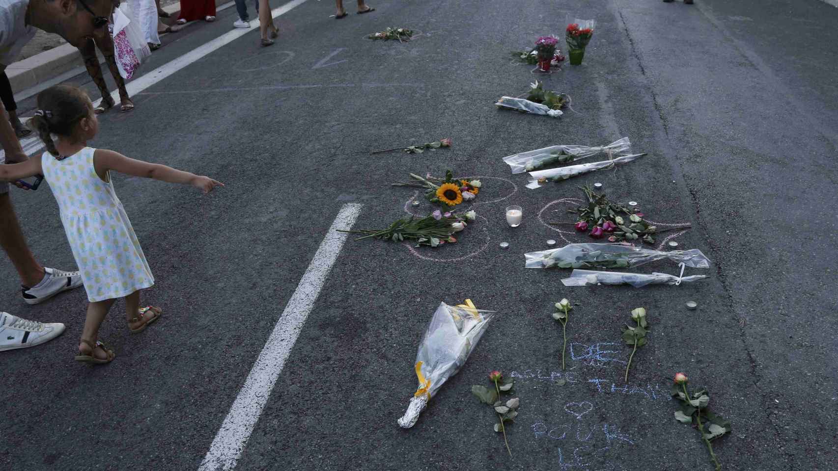 Manchas de sangre del atentado, cubiertas por flores y velas.