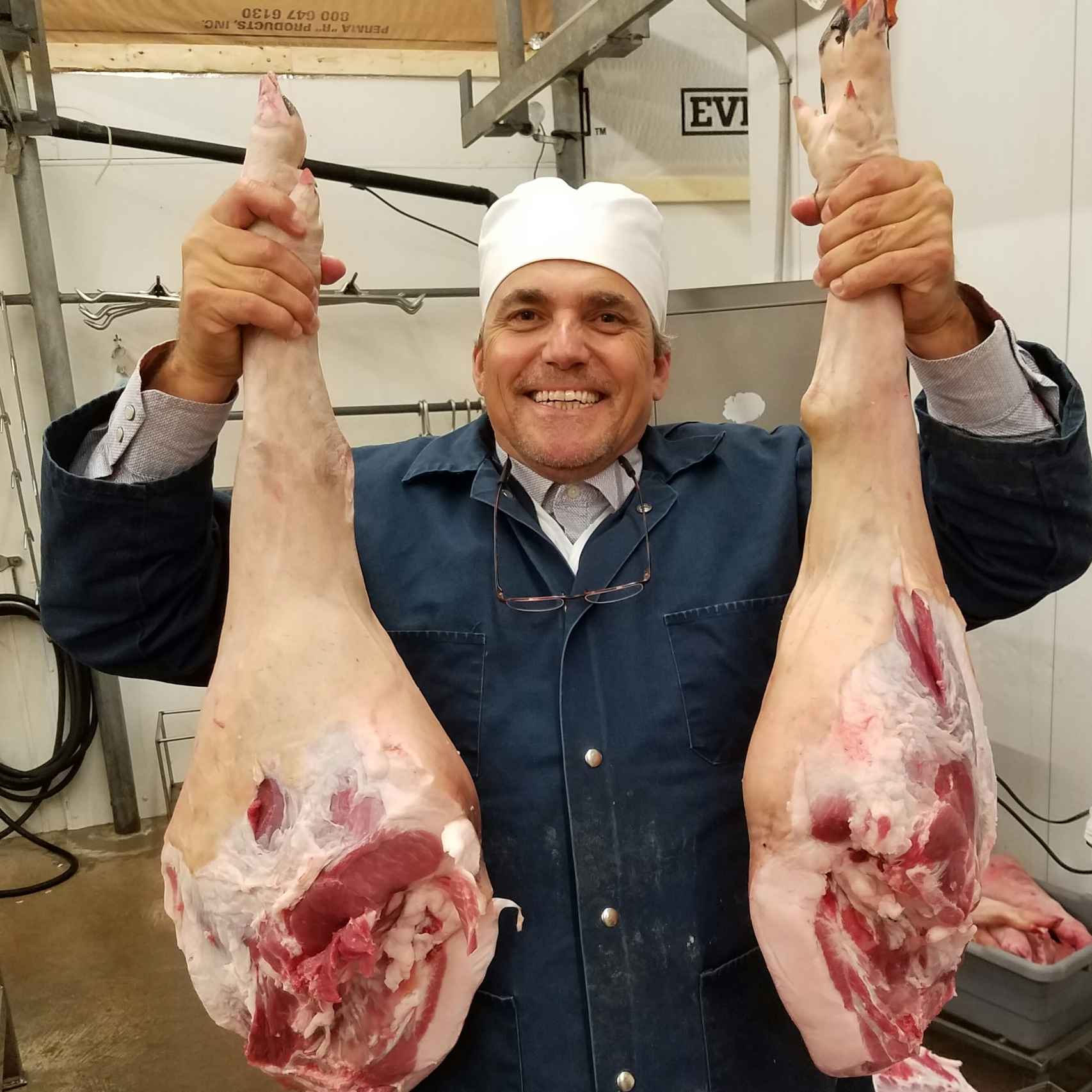 Sergio cogiendo dos patas de jamón fabricadas en Flatonia.