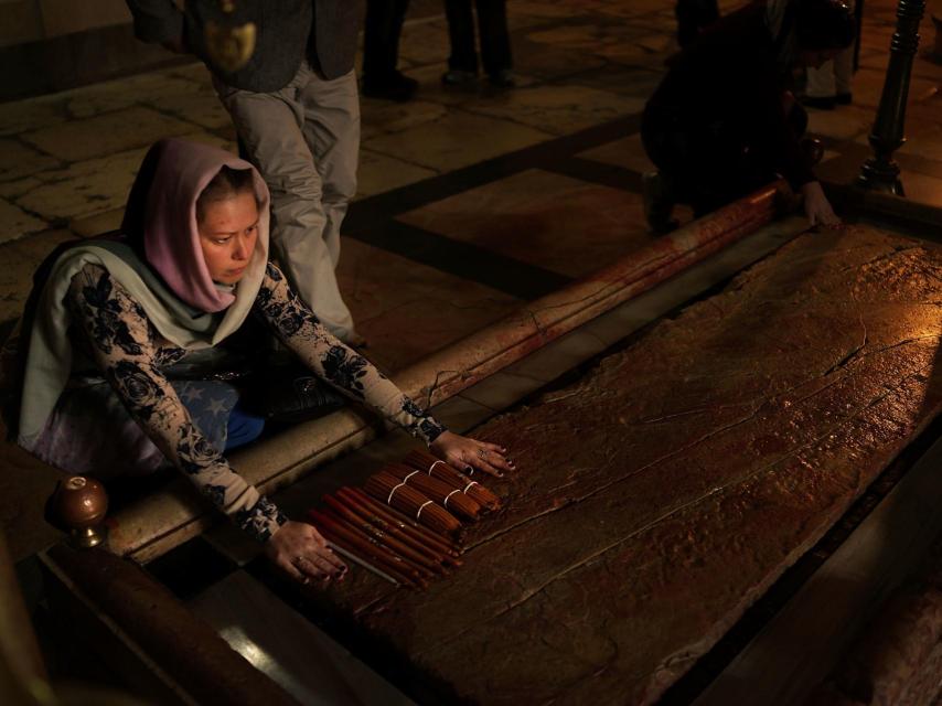 Los visitantes del Santo Sepulcro tocan y besan la piedra sobre la que se cree que yació Jesús.