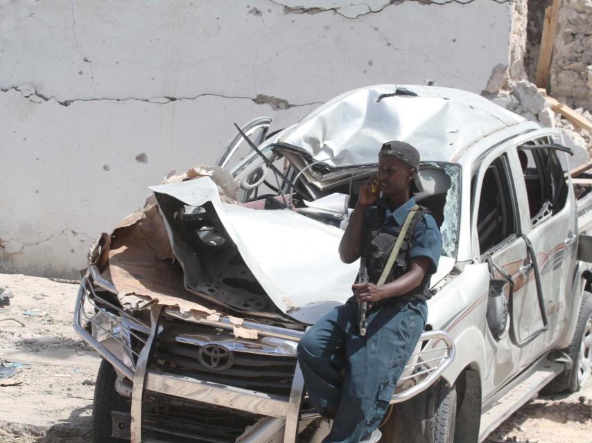 Un policía apoyado en un coche destruido tras la explosión.