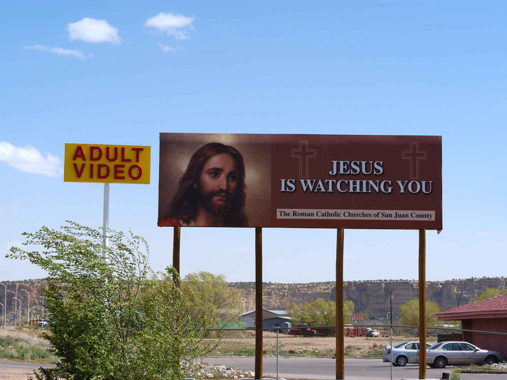 Un cartel de una iglesia junto a un anuncio de un sex shop.