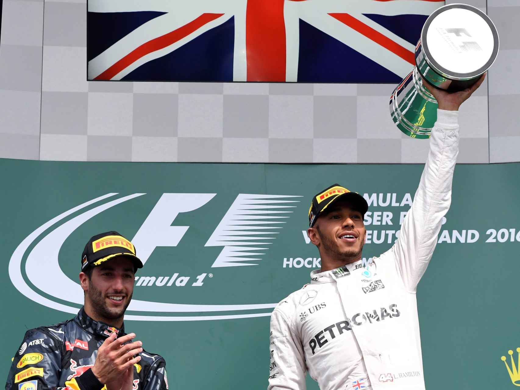 Hamilton levanta el trofeo de vencedor en el podio escoltado por Ricciardo.