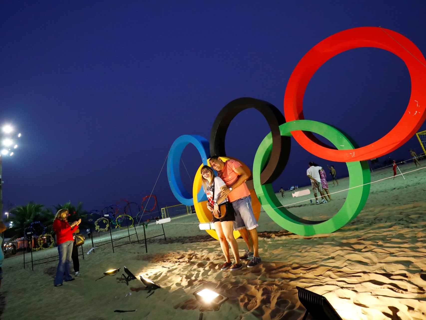 Unos aficionados posan delante de los anillos olímpicos.