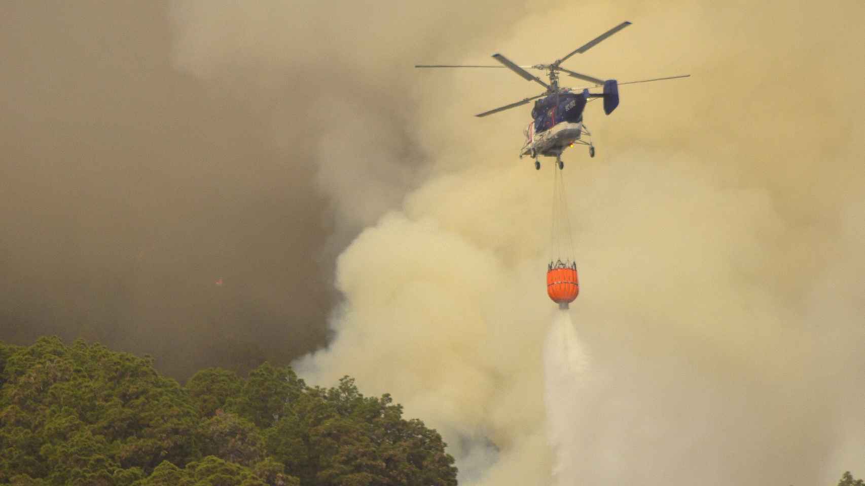 Un helicóptero descarga agua sobre el fuego que comenzó ayer en el municipio palmero de El Paso