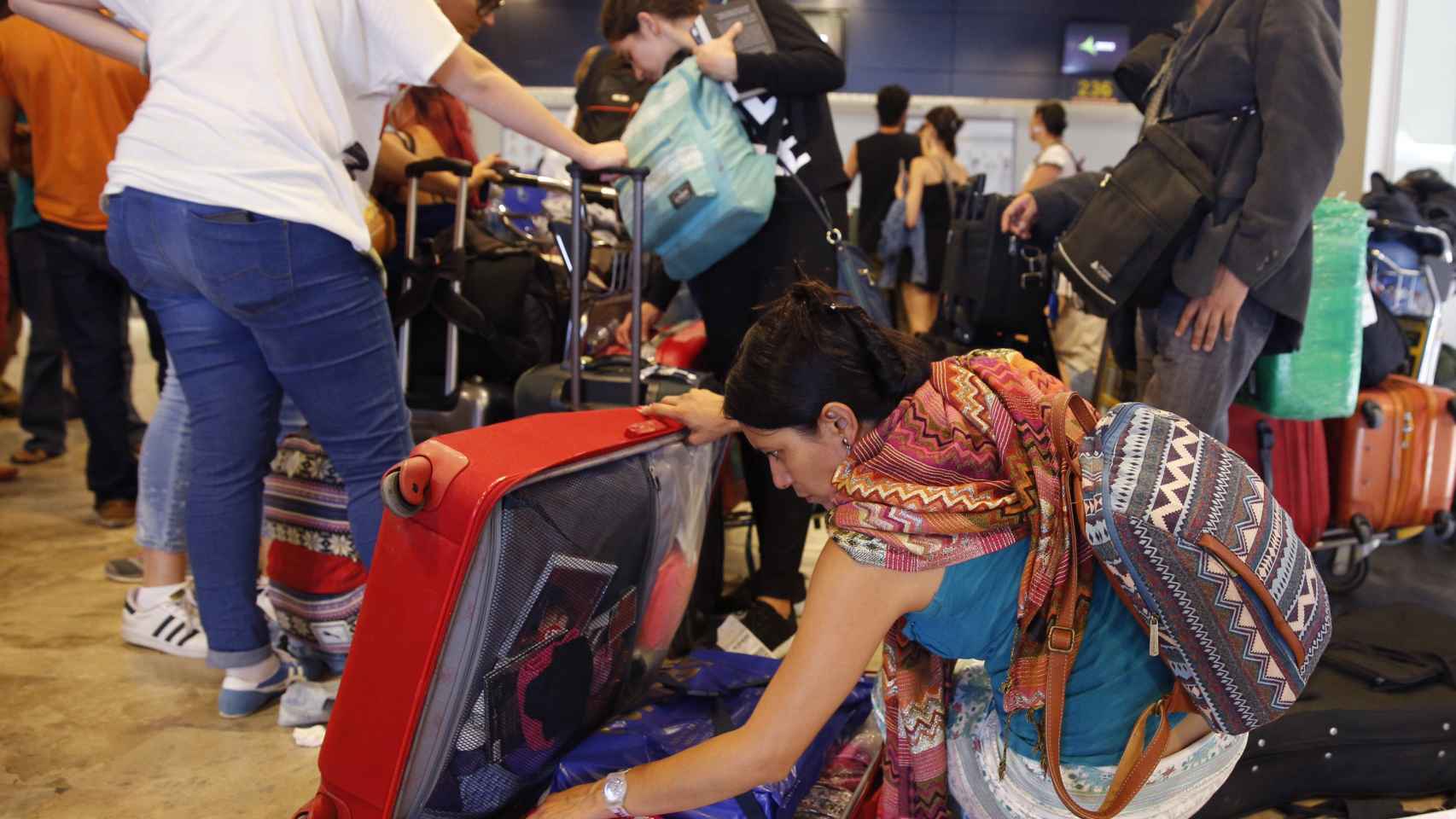 Una mujer busca entre sus pertenencias en el aeropuerto.