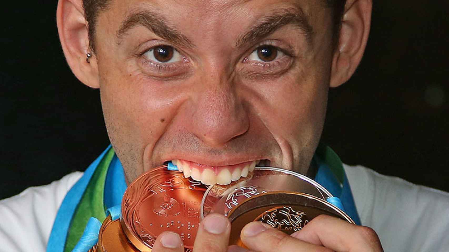 Thiago Pereira muerde sus medallas.