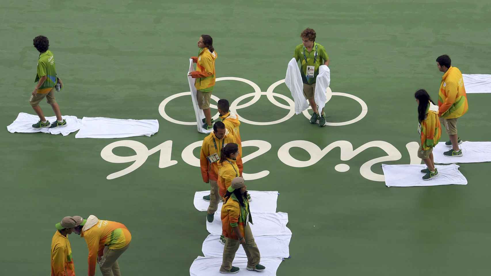 Los voluntarios brasileños limpian la pista de tenis.